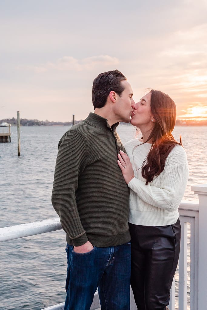 couple kisses in front of newport sunset for proposal photographer