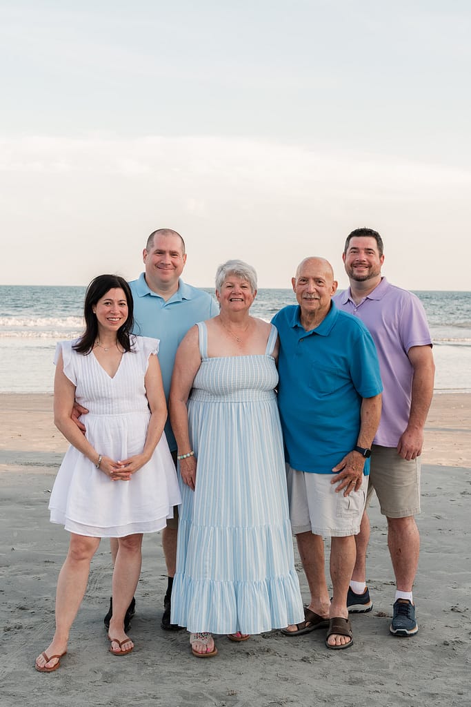 family smiles for photos on beach