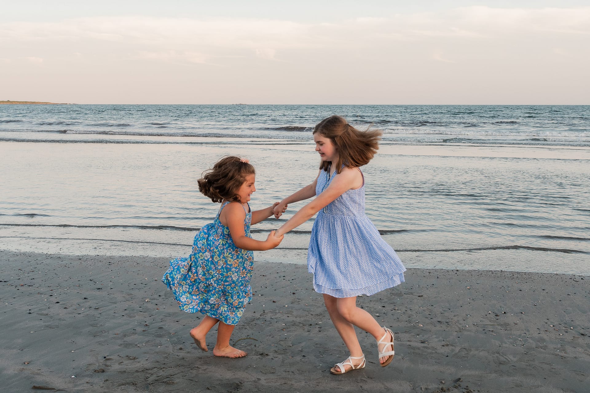 girls play in family portraits on beach