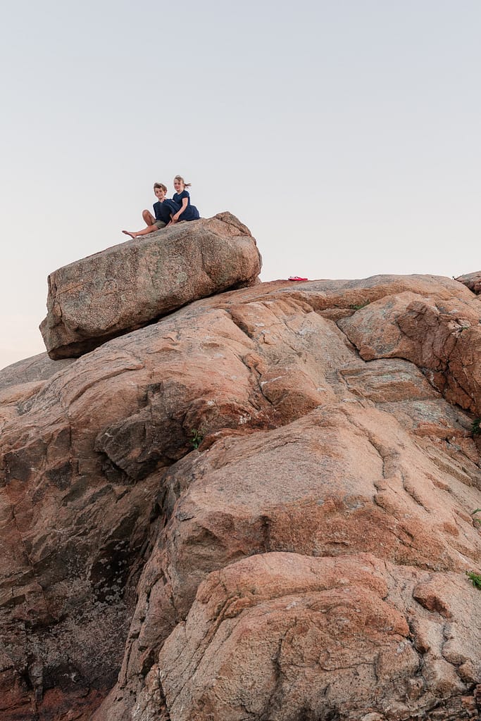 two children sit on a rock
