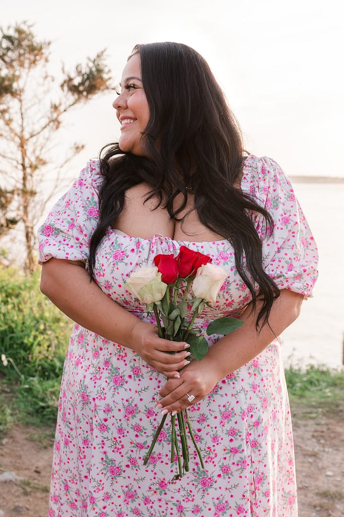 woman holds bouquet of roses with engagement ring