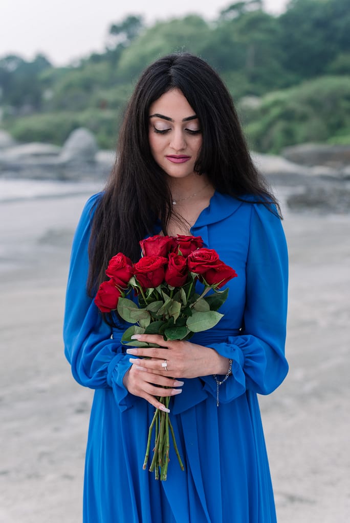 woman holds roses on beach