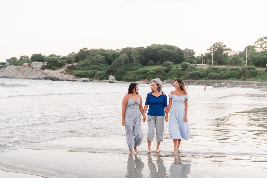 mom and daughters walk on beach