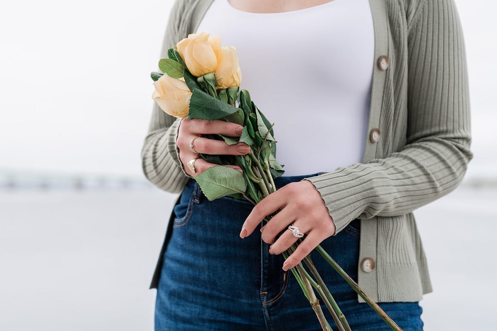 woman holds roses with engagement ring