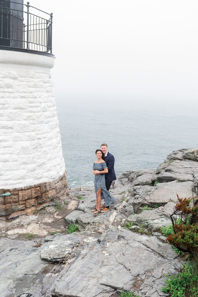 couple poses near lighthouse at castle hill inn in newport after marriage proposal