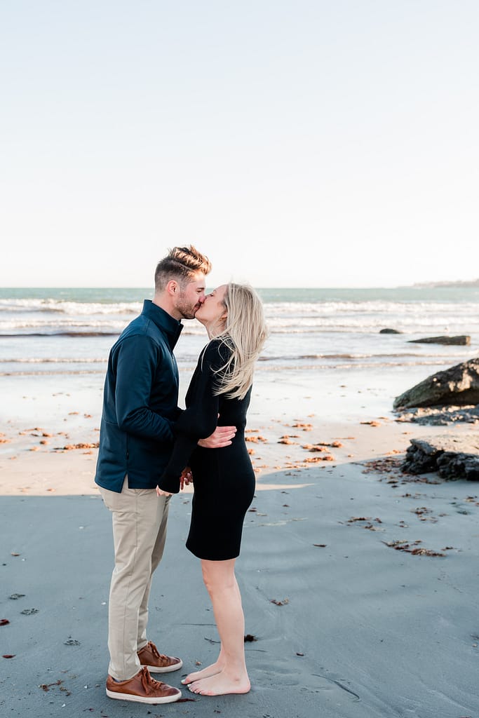 couple kisses after proposal on beach