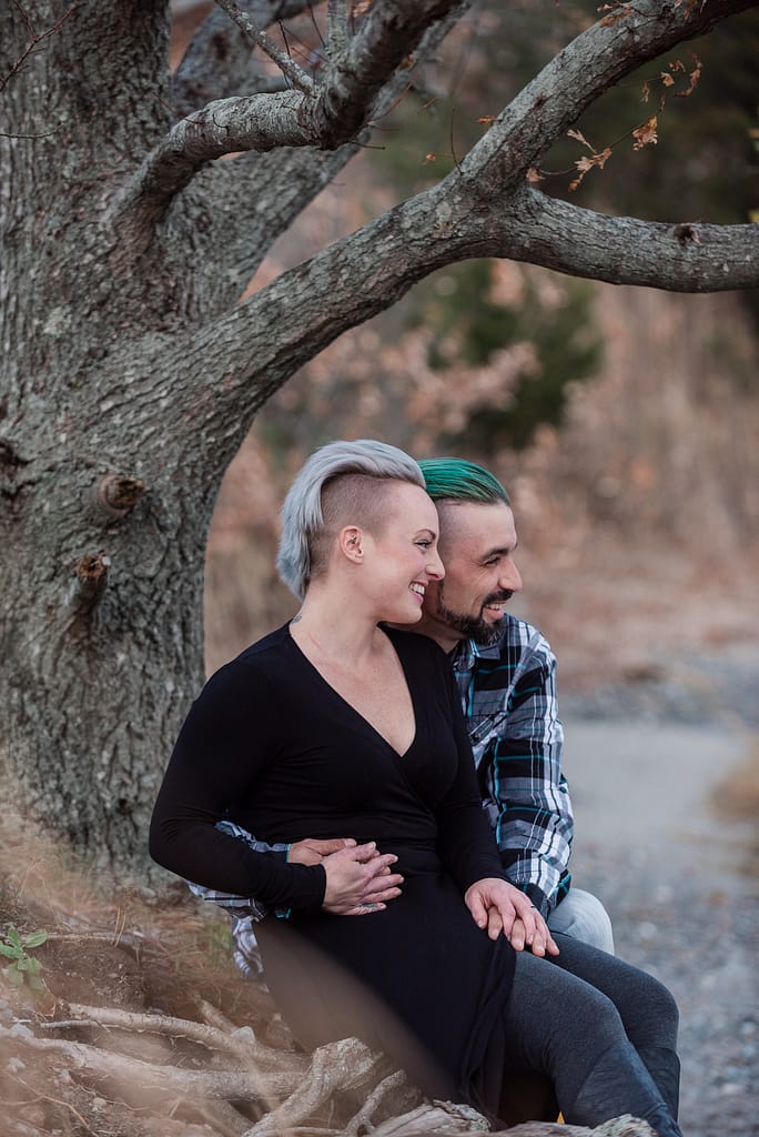 couple sits under tree for engagement photos