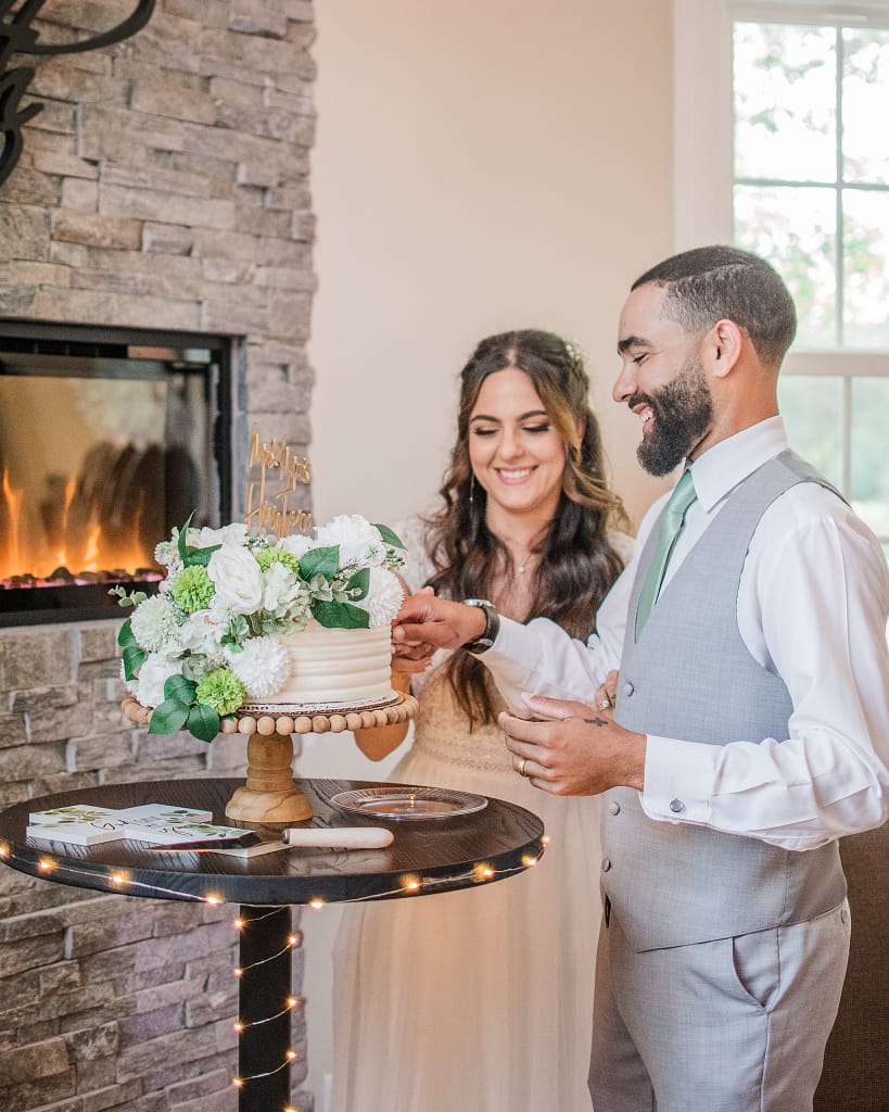light and airy wedding photo of couple cutting the cake near a bright window
