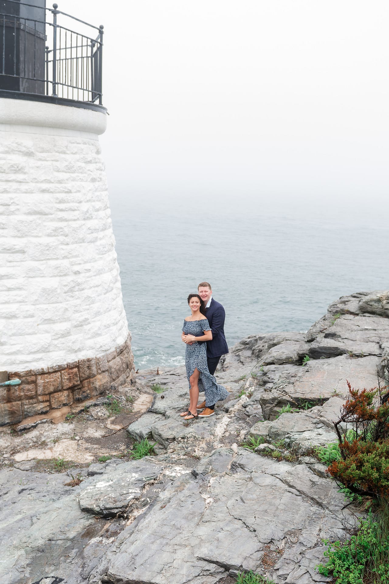 couple poses near lighthouse at castle hill inn in newport after marriage proposal